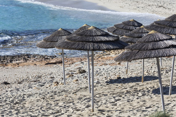Detail of woven umbrellas above rows on beach in Cyprus.