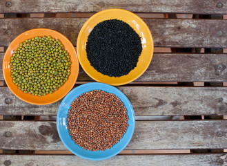 Three bowls with different seeds on wooden background