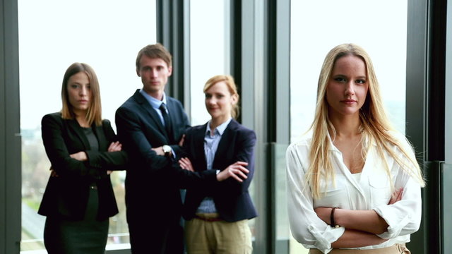 Portrait of attractive blonde businesswoman, colleagues in background