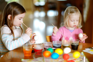 Two little sisters painting colorful Easter eggs