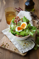 Salad with bacon and eggs in a bowl on a wooden background