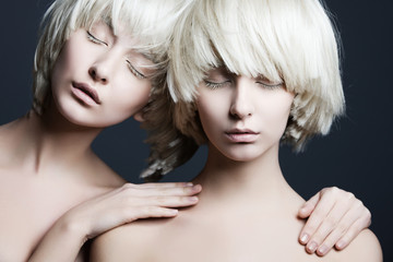 Portrait of two beautiful girls twins with closed eyes in studio - obrazy, fototapety, plakaty