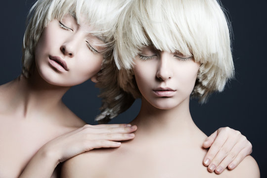 Portrait of two beautiful girls twins with closed eyes in studio