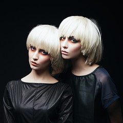 Naklejka premium Portrait of two beautiful girls twins in the studio on a black background