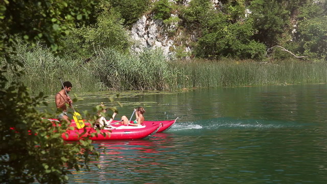 Man jumping off canoe into river, friends laughing