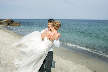 Fototapeta na wymiar a young couple running at the beach, wedding at the sea, beautiful white wedding dress