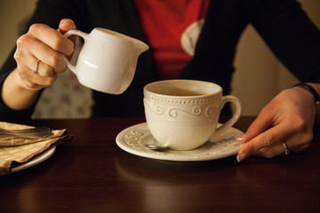 a Cup of coffee and a jug in girls hands
