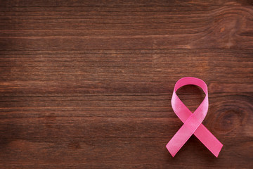 Pink ribbon - symbol of breast cancer awareness. Wooden background.