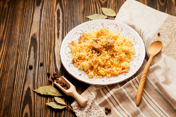 
national cuisine , stewed rice with meat , which is called pilaf with bay leaf and pepper on a wooden background 