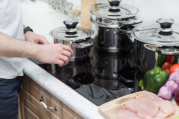 Man prepares dinner on modern induction cooker