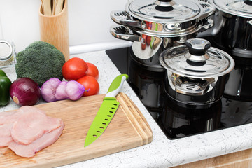 Ingredients for a healthy lunch and modern induction cooker with the silver pots.