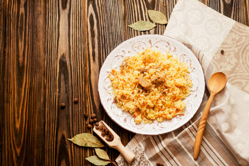 
national cuisine , stewed rice with meat , which is called pilaf with bay leaf and pepper on a wooden background 