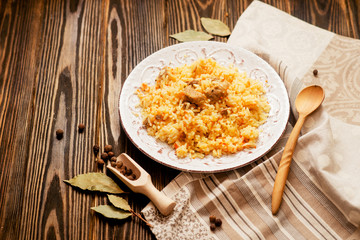 
national cuisine , stewed rice with meat , which is called pilaf with bay leaf and pepper on a wooden background 