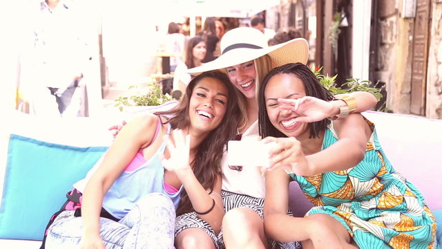 Beautiful young women having fun taking selfies in town