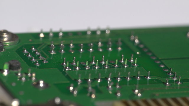 Side turning view of a green textolite circuit board with lead pins