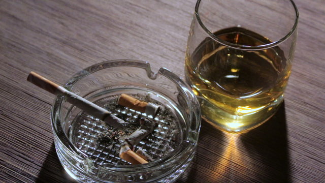 Сigarette and glass of whiskey on the table