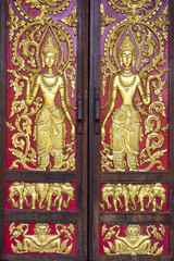 Fototapeta na wymiar Gold carve women on red background / Chiang Mai public temple door