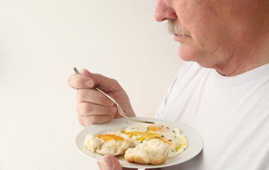 Man having fried eggs and biscuit with copy space 