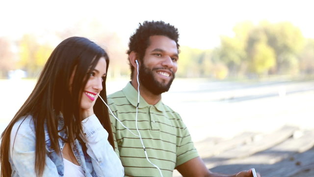 Young couple sharing earphones while listening to music