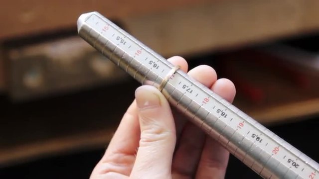 The method of measuring the size of the gold ring. Production and making manufacturing, factory, cast craft design, process precious gold jewelry, diamond, jewels, ring jeweler, goldsmith in workshop.