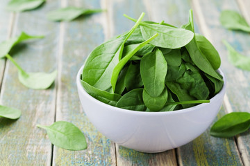 Fresh spinach leaves in bowl on rustic kitchen table, organic food