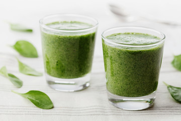 Green spinach smoothie in glass on white table, detox and diet food for breakfast