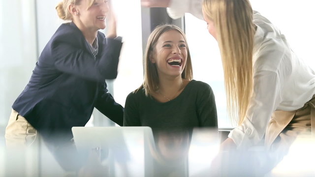 Three beautiful business woman cheering and high-fiving in office meeting