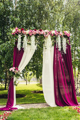 lilac wedding arch with flowers on ceremony place