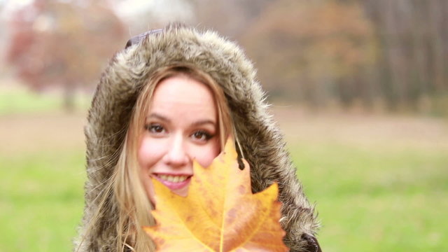 Young woman playing with leaf and smiling