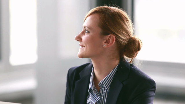 Young businesswoman listening and nodding during corporate presentation