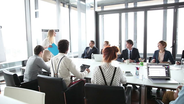 Business people sitting at table while female colleague giving presentation 