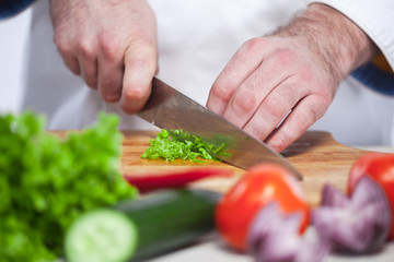 Chef cutting a green lettuce his kitchen