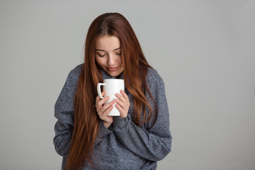 Beautiful smiling young woman feeling cold and drinking hot tea