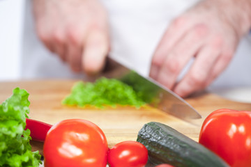 Chef cutting a green lettuce his kitchen
