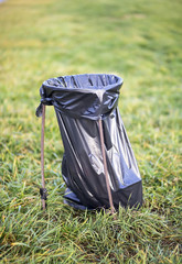 Plastic trash bag in a green park