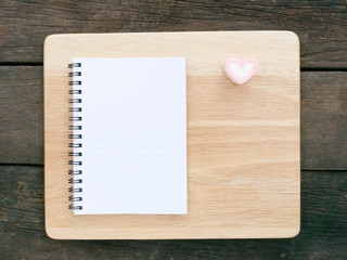 The white note book and lovely pink heart marshmallow and wooden board on the old deep brown planks background for Valentine's day.