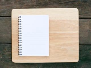 The white note book and wooden board on the old deep brown planks background.