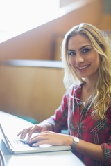Smiling female student using laptop