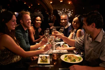 Zelfklevend Fotobehang Group Of Friends Enjoying Meal In Restaurant © Monkey Business