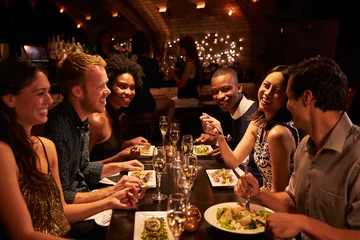 Rolgordijnen Group Of Friends Enjoying Meal In Restaurant © Monkey Business