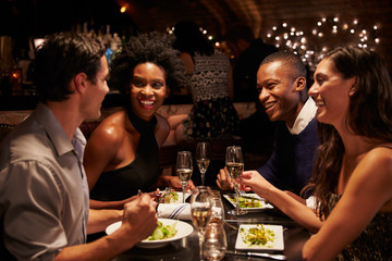 Two Couples Enjoying Meal In Restaurant Together