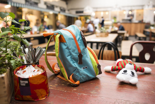 Colored child's rucksack and toy on a wooden table