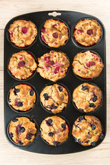 Black baking sheet with blueberry and raspberry cupcakes