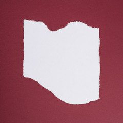 Piece of torn paper over the dark red background