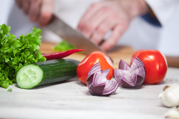 Chef cutting a green lettuce his kitchen