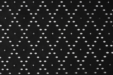 Black perforated striped paper sheet texture background. Ovals, squares, flowers shapes embossed pattern.