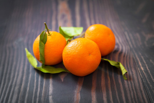 Three ripe tangerine on a wooden table