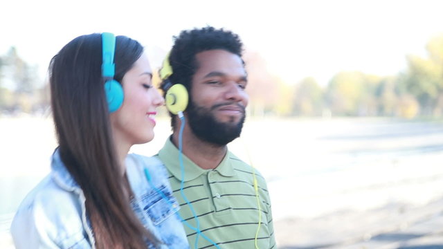Happy couple with headphones listening to music and dancing 