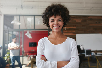 Smiling young woman standing in creative office - Powered by Adobe