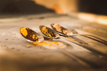 Spice spoons laid on the table (turmeric, curry and ginger), filtered with vintage colors